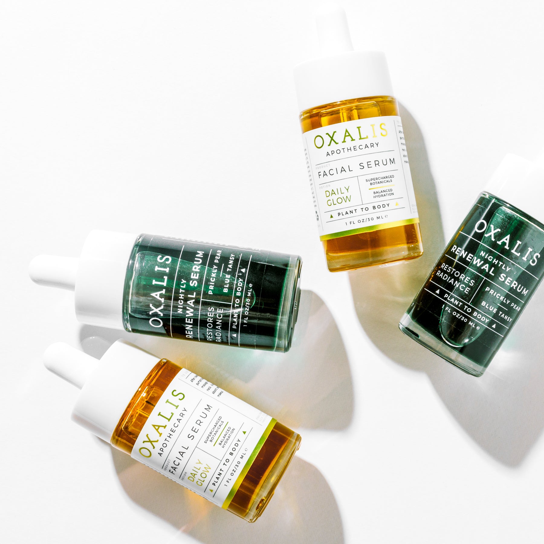 Overhead view of Oxalis Apothecary facial serums featuring the Daily Glow morning serum and Nightly Renewal evening serum on a clean white background.