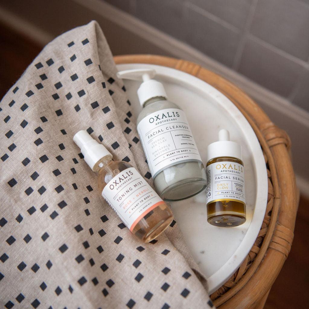 Oxalis Apothecary plant-powered skincare routine featuring Rose Neroli Toning Mist, French Sea Clay Facial Cleanser, and Daily Glow Facial Serum.