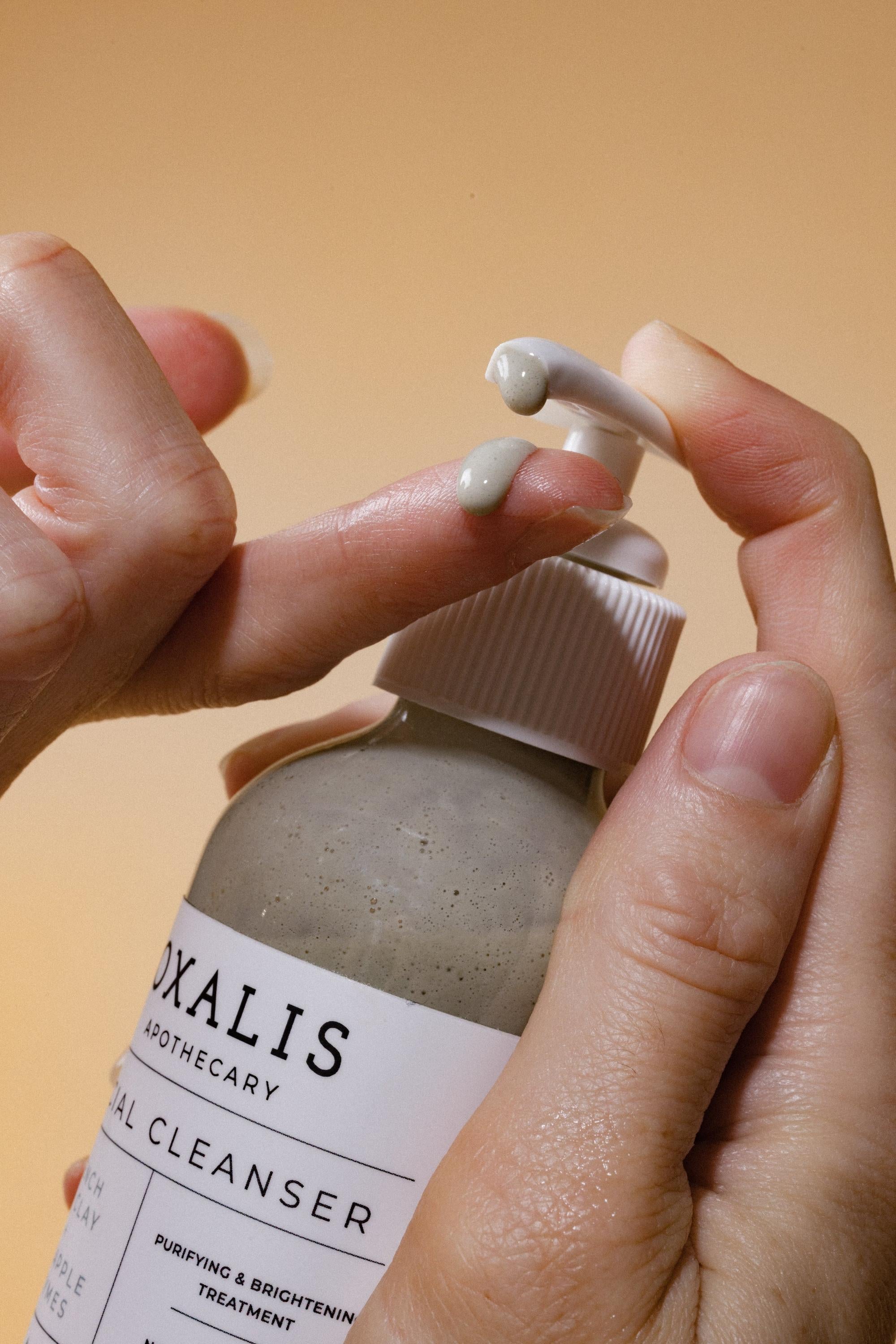 Oxalis Apothecary Facial Cleanser dispensed onto a finger, showing the purifying French Sea Clay texture.