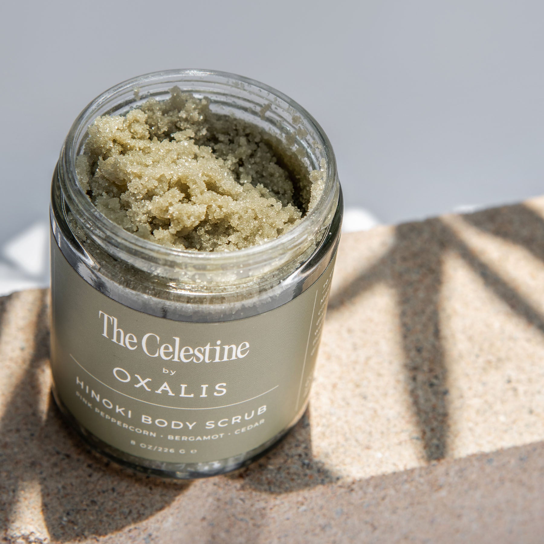 Open jar of The Celestine by Oxalis Apothecary Hinoki Body Scrub, a handcrafted natural exfoliator featuring notes of pink peppercorn, bergamot, and cedar.