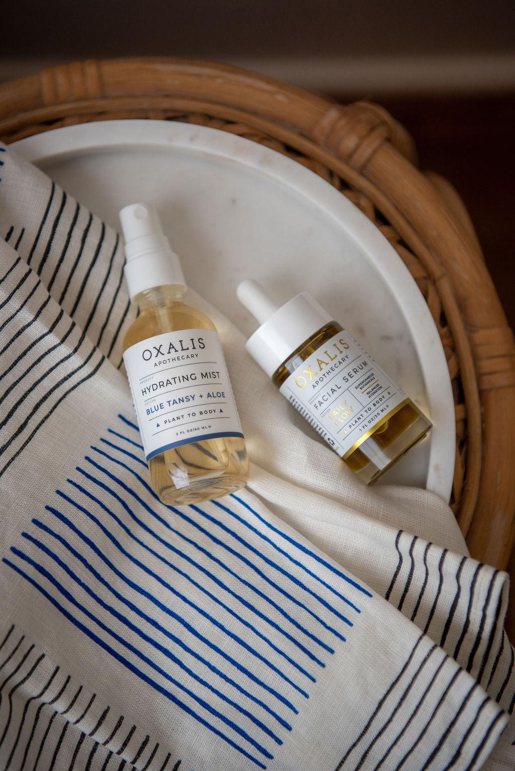 Oxalis Apothecary Hydrating Mist and Daily Glow Facial Serum on a marble tray